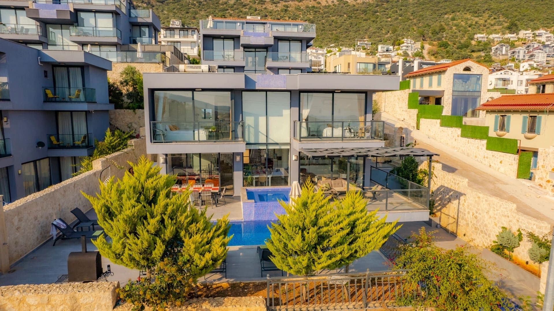 Mavi renkli modern villanın havuzlu bahçesi ve geniş camları