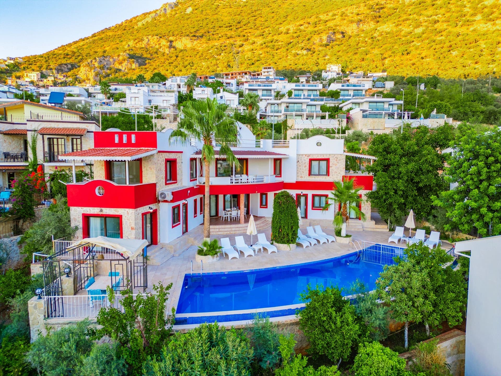 Kırmızı detaylı beyaz villanın yüzme havuzlu geniş bahçesi