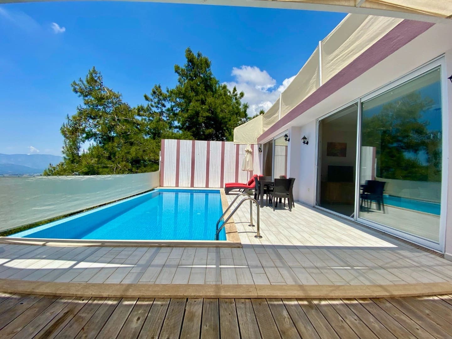 Açık mavi yüzme havuzu ve şezlongların yer aldığı villa terası.