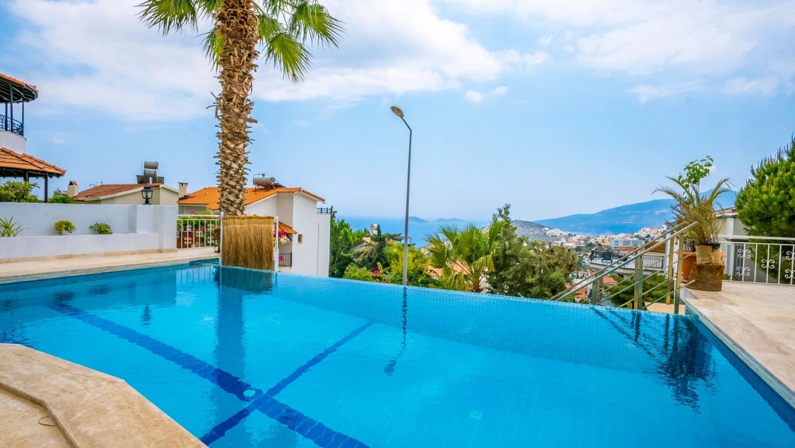 Deniz manzaralı ve palm ağaçlı açık havuz terası.