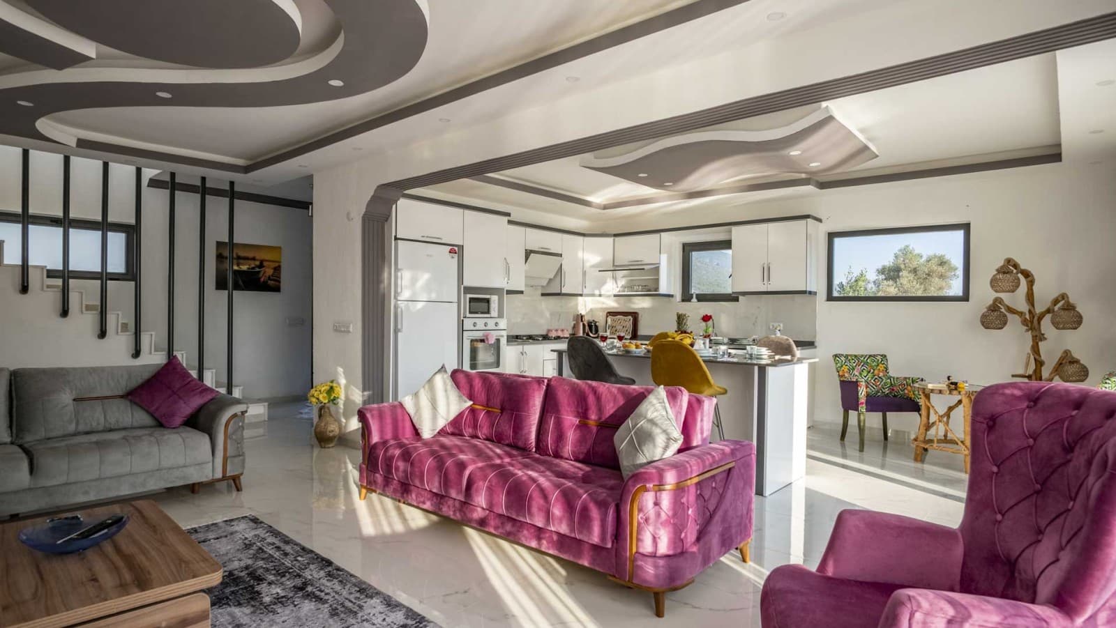 Mor koltuk takımı ve arka planda açık mutfak bulunan modern iç mekân.