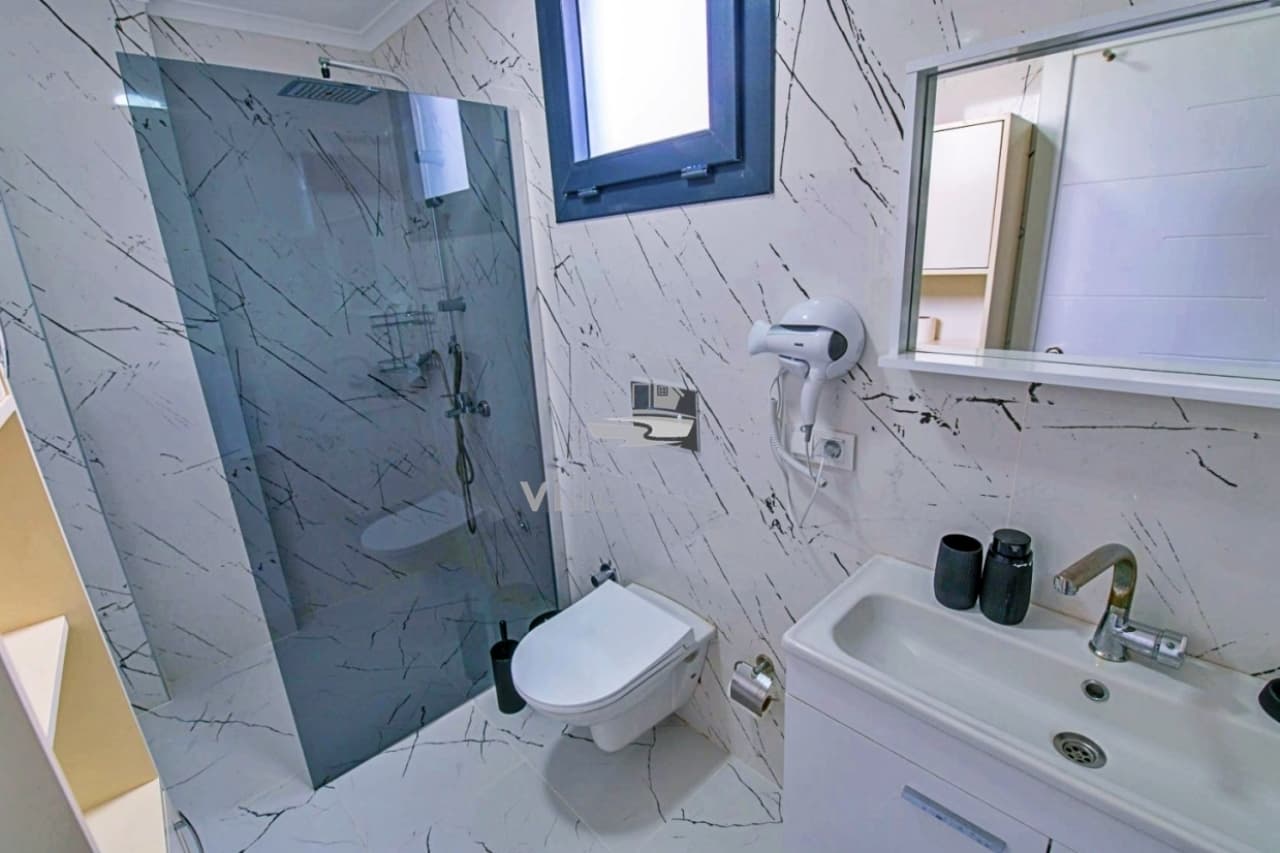 Mermer desenli duvarları olan banyo, duşakabin ve lavabo.