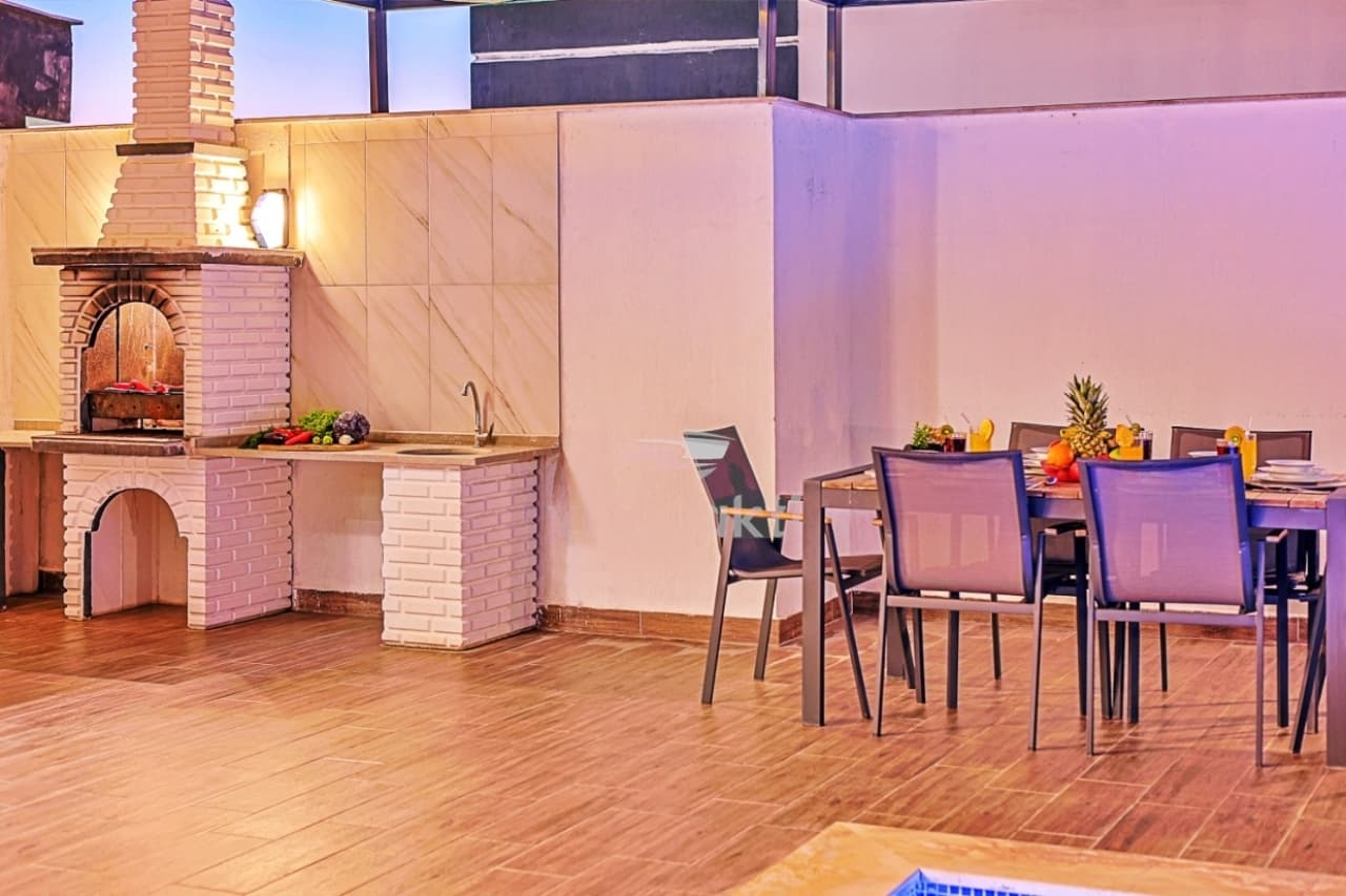 Taş detaylı barbekü köşesi ve yemek masasının bulunduğu teras alanı.