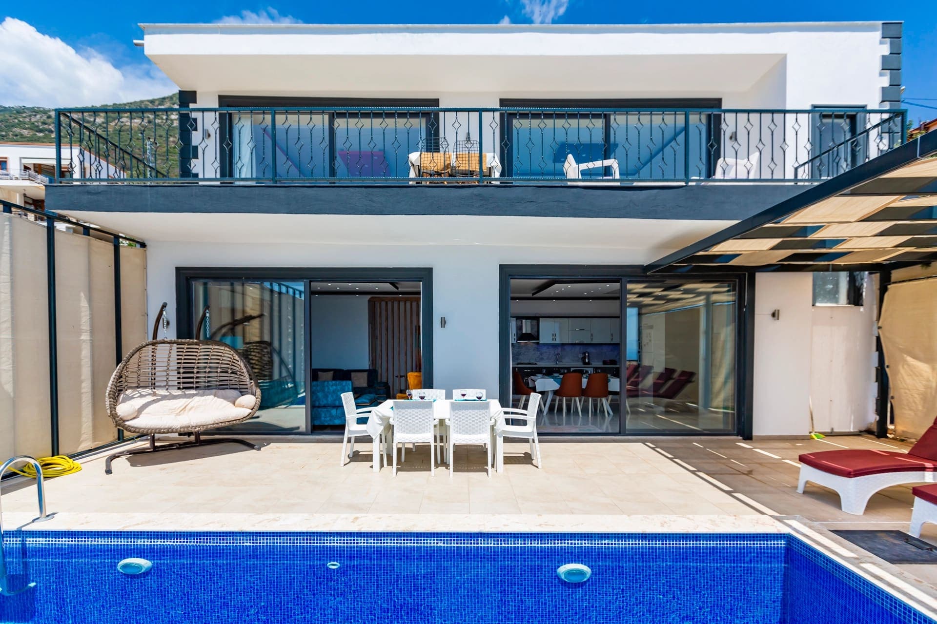 Önünde havuz bulunan, balkonlu ve beyaz cepheli iki katlı villa.