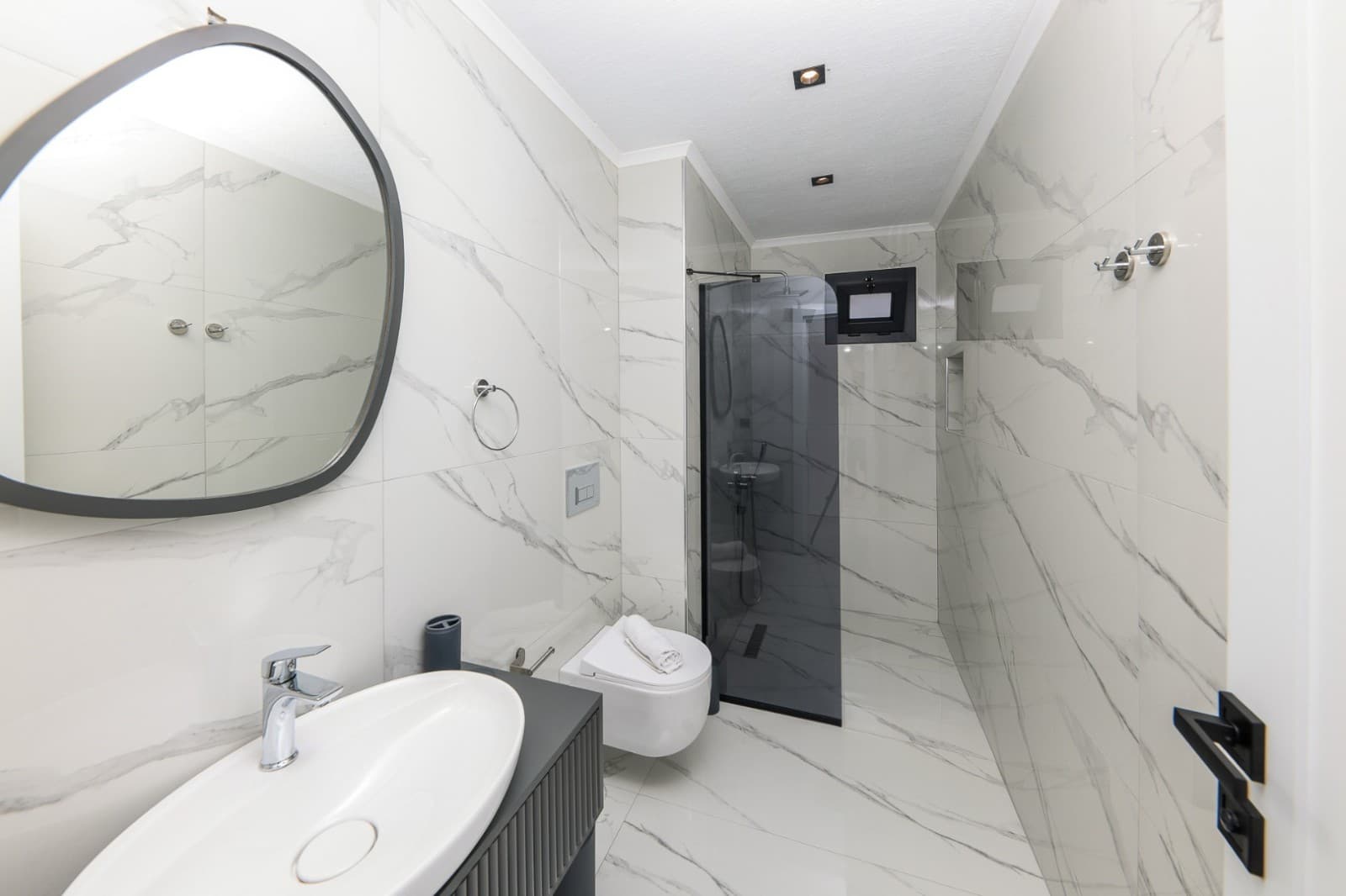 Mermer kaplı duvarları olan modern banyo ve duş kabini