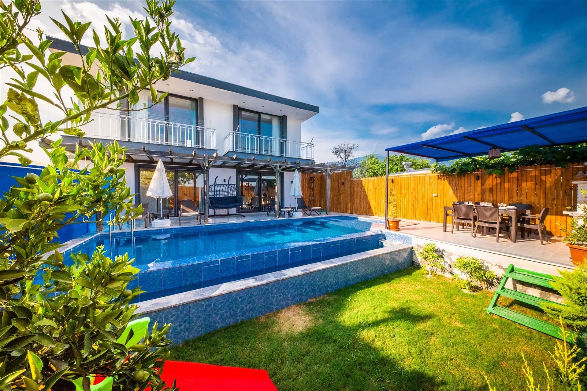 Bahçesinde havuz ve çim alan bulunan iki katlı villa.