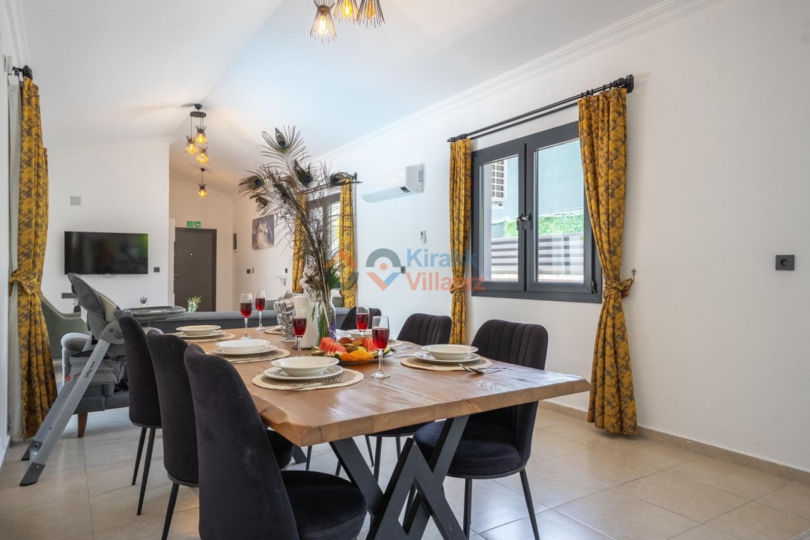 Ahşap yemek masası, siyah sandalyeler, sarı perdeler ve tavandan sarkan modern aydınlatmalar.