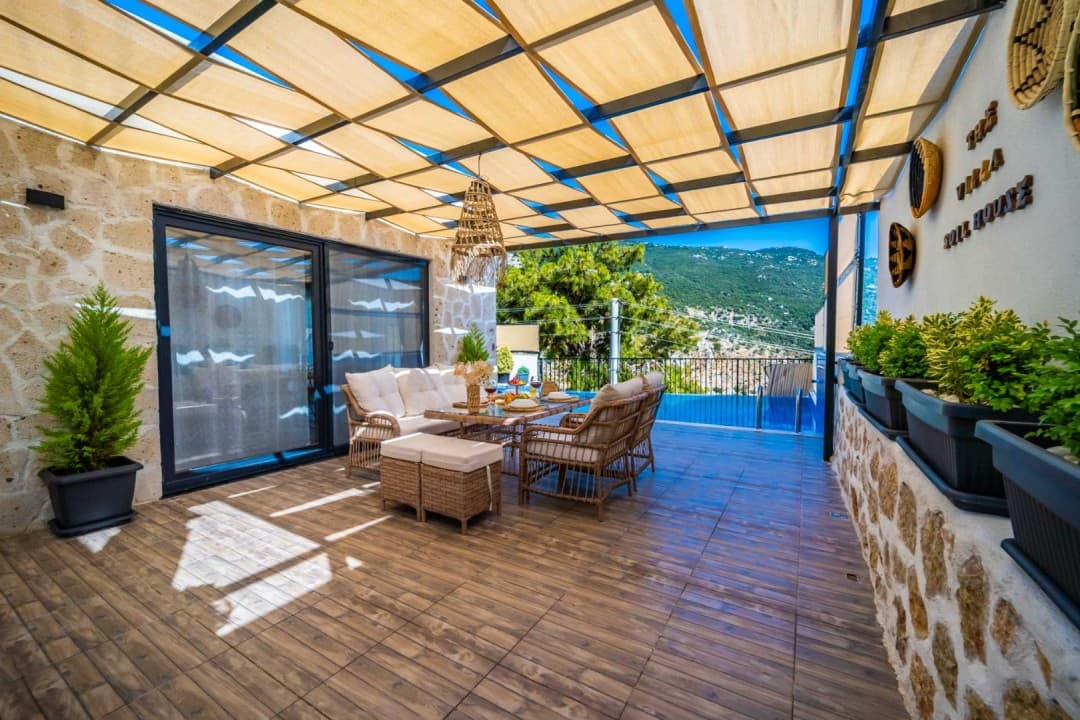 Bej tente gölgelikli terasta rattan oturma grubu, yemek masası ve havuz manzarası.