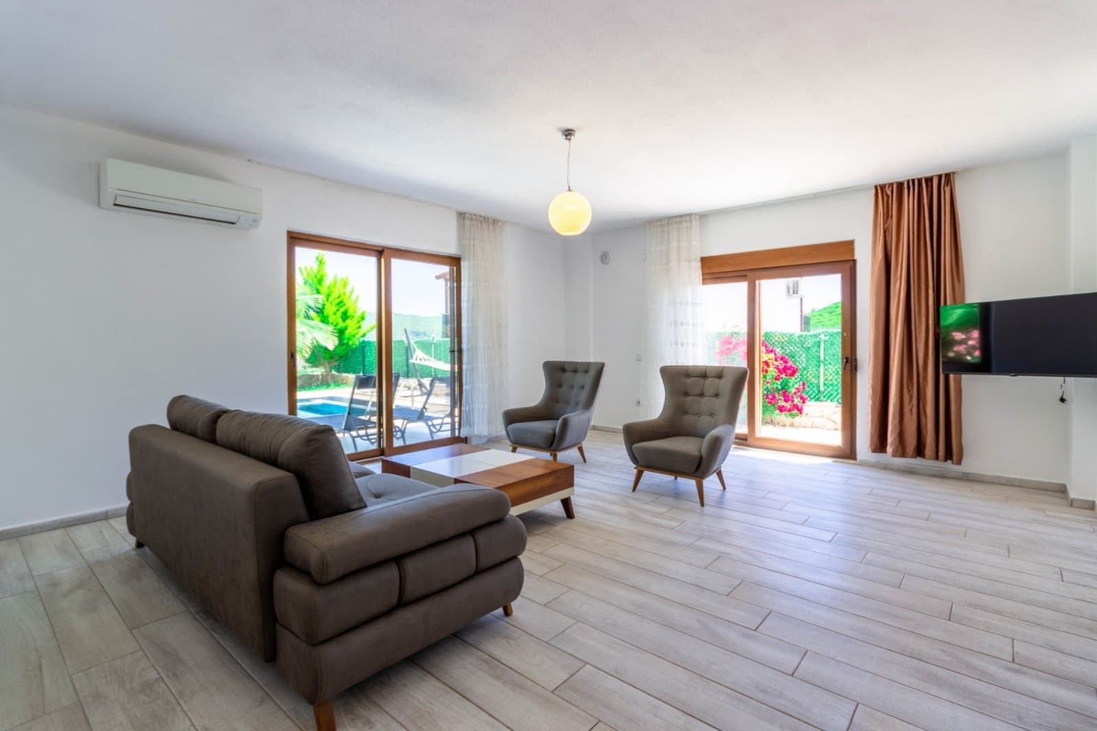 Gri koltuk takımı ve bahçeye açılan sürgülü kapıları olan salon