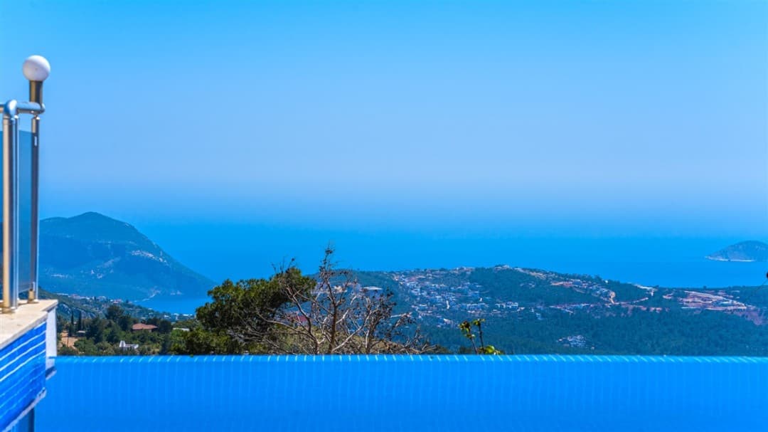 Sonsuzluk havuzunun kenarından görünen deniz, dağlar ve yerleşim yeri manzarası.
