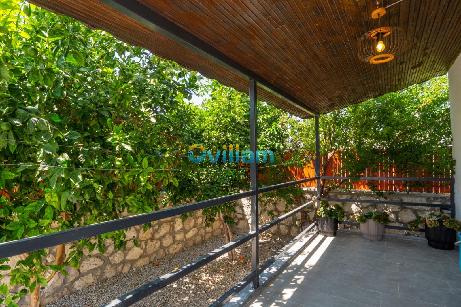 Ağaçlarla çevrili ve ahşap tavanlı balkon alanı.