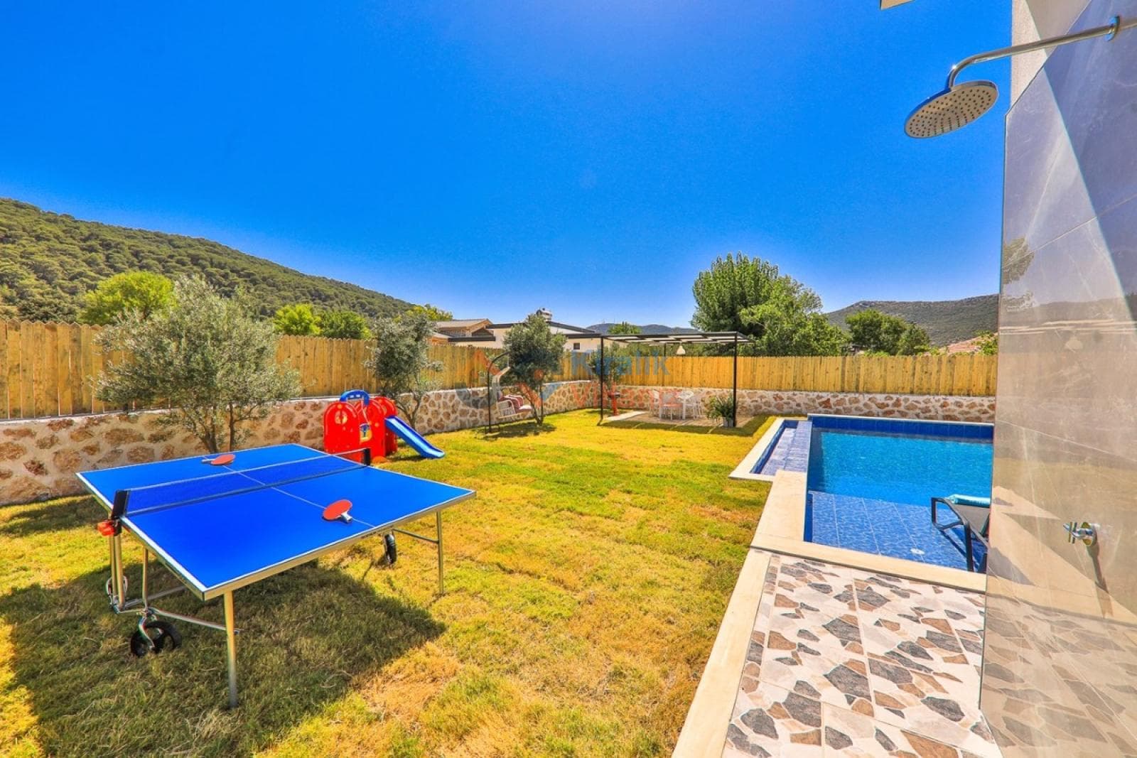 Bahçesinde havuz ve masa tenisi bulunan villa.