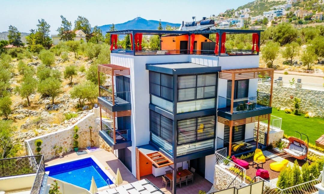 Dağ ve yeşillik manzaralı çok katlı modern villa dış cephesi.
