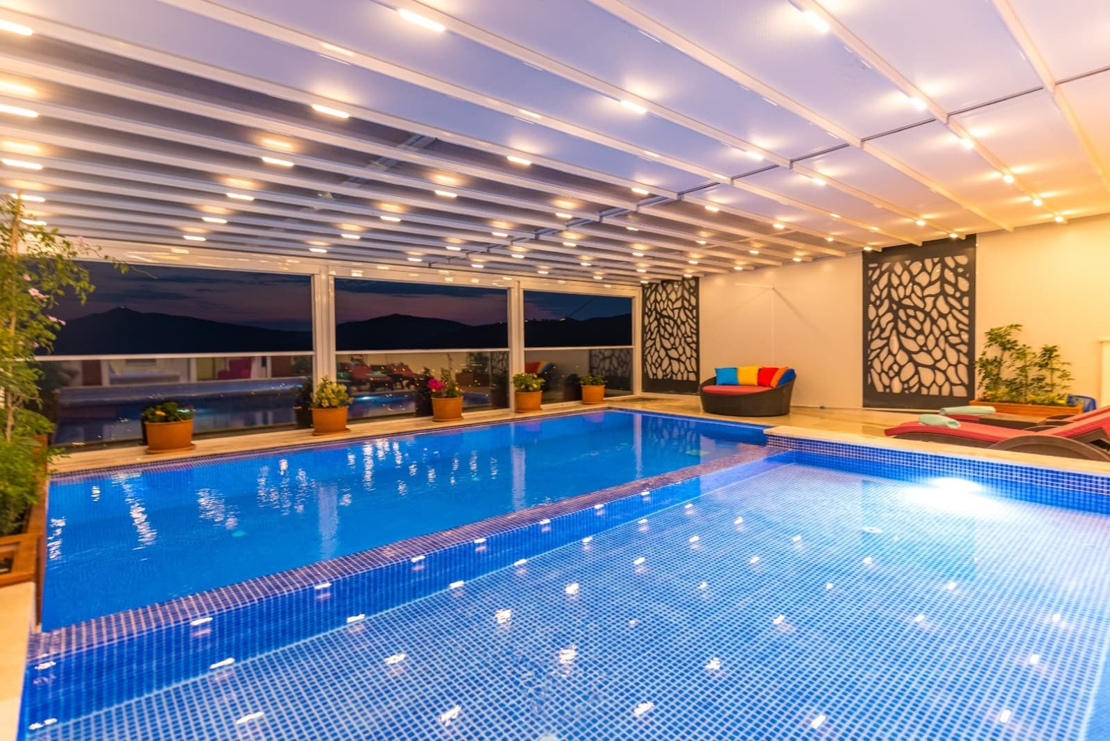 Işıklı modern tavanı ve cam pencereleri olan kapalı yüzme havuzu.