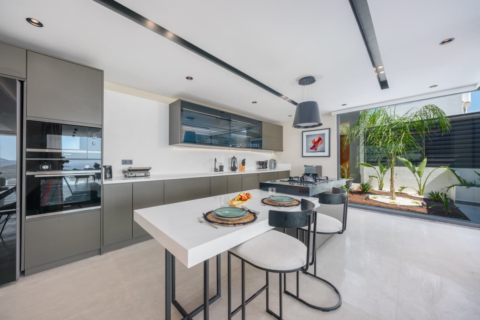 Gri dolaplı, mermer tezgahlı ve orta adalı modern mutfak alanı.