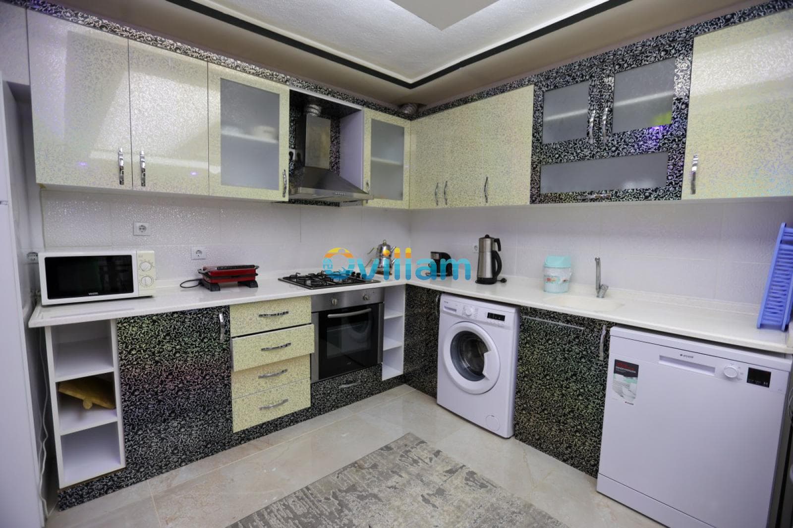 Desenli dolap kapaklarına sahip modern mutfak tezgahı, beyaz eşyalar ve ocak.