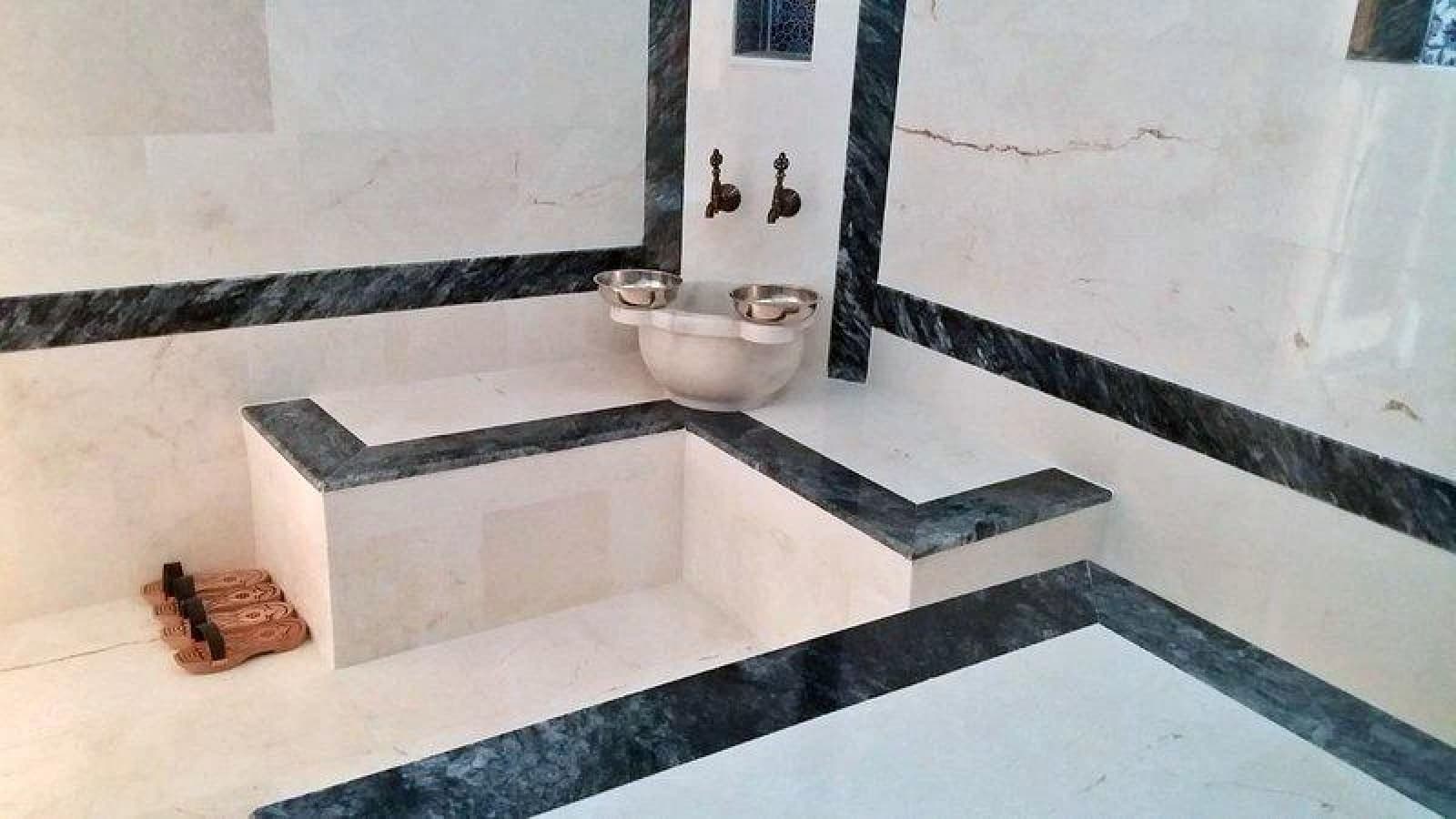 Beyaz mermer kaplı duvar ve oturma alanına sahip geleneksel hamam köşesi.