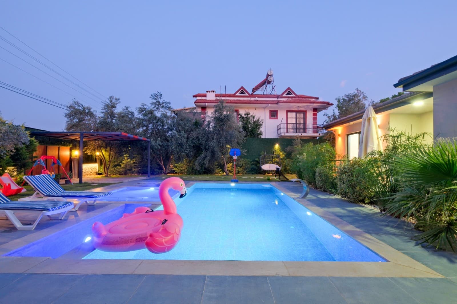 Akşam saatlerinde aydınlatılmış havuz ve pembe flamingo deniz yatağı