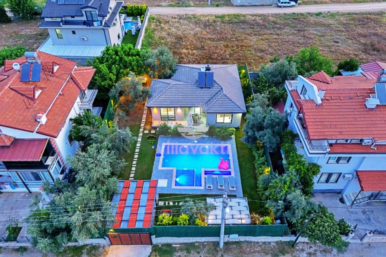 Kuş bakışı görünümde bahçeli villa, yüzme havuzu ve çevresindeki yeşil alanlar.