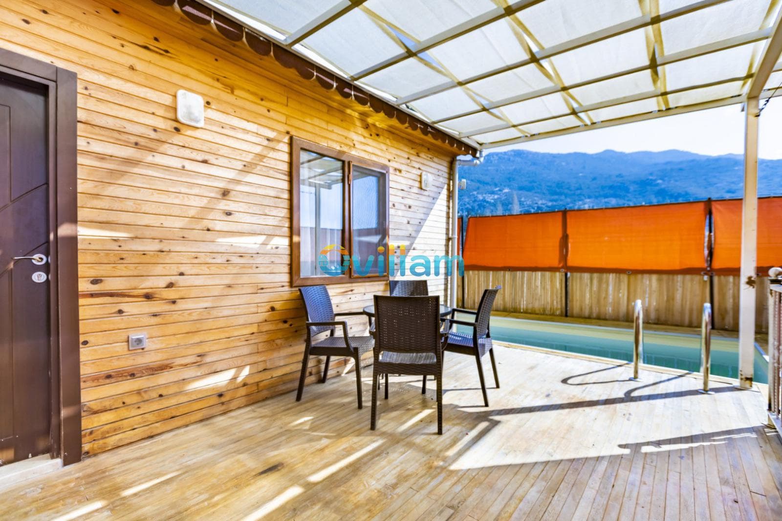 Ahşap kaplamalı verandada masa, sandalyeler ve havuz manzarası.