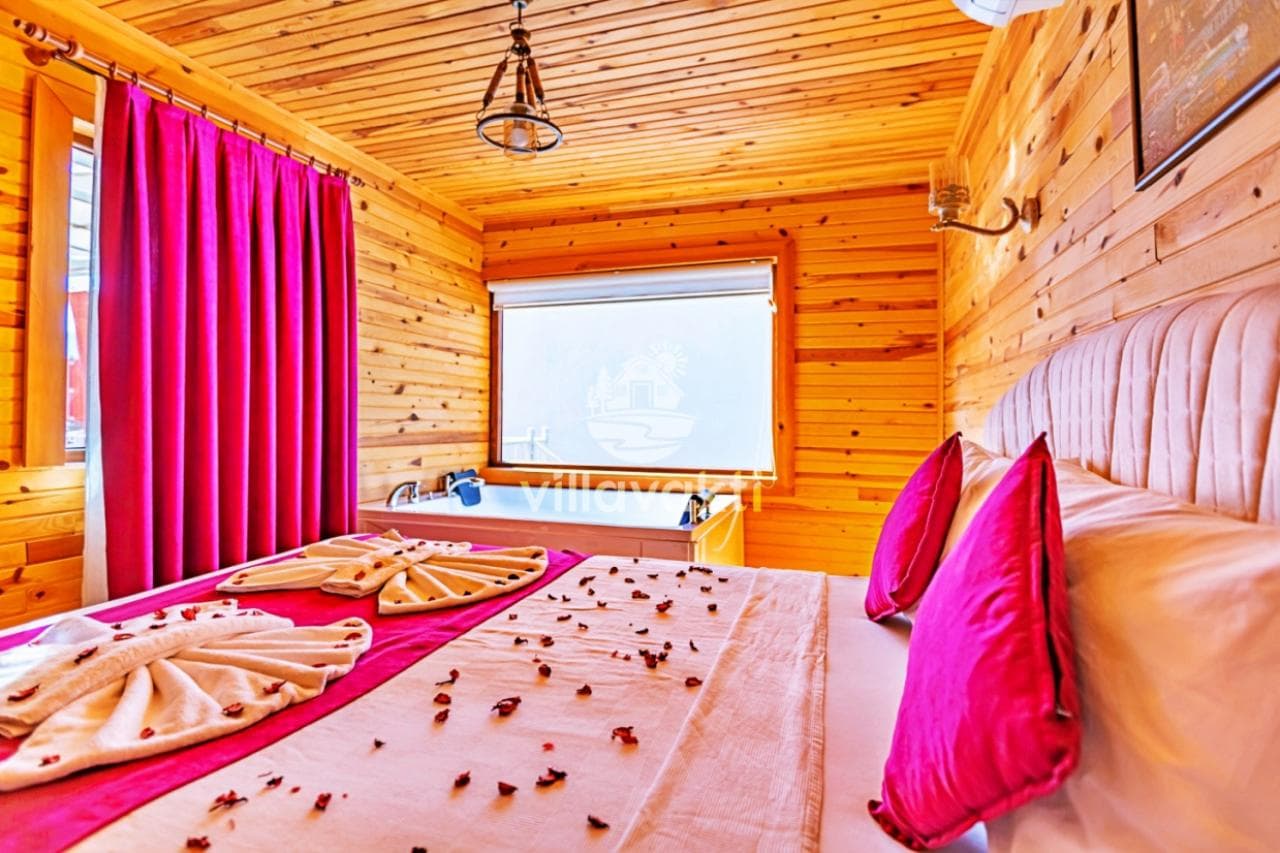Ahşap kaplamalı, çift kişilik yataklı ve yatak ucunda jakuzi bulunan yatak odası.
