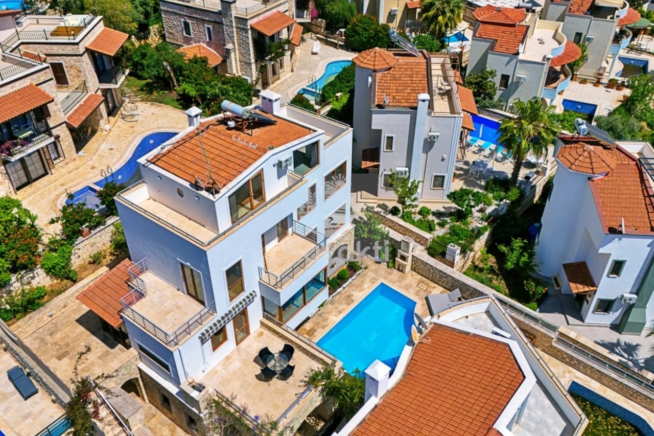 Kiremit çatılı villaların ve havuzların bulunduğu yerleşimin kuş bakışı görünümü.