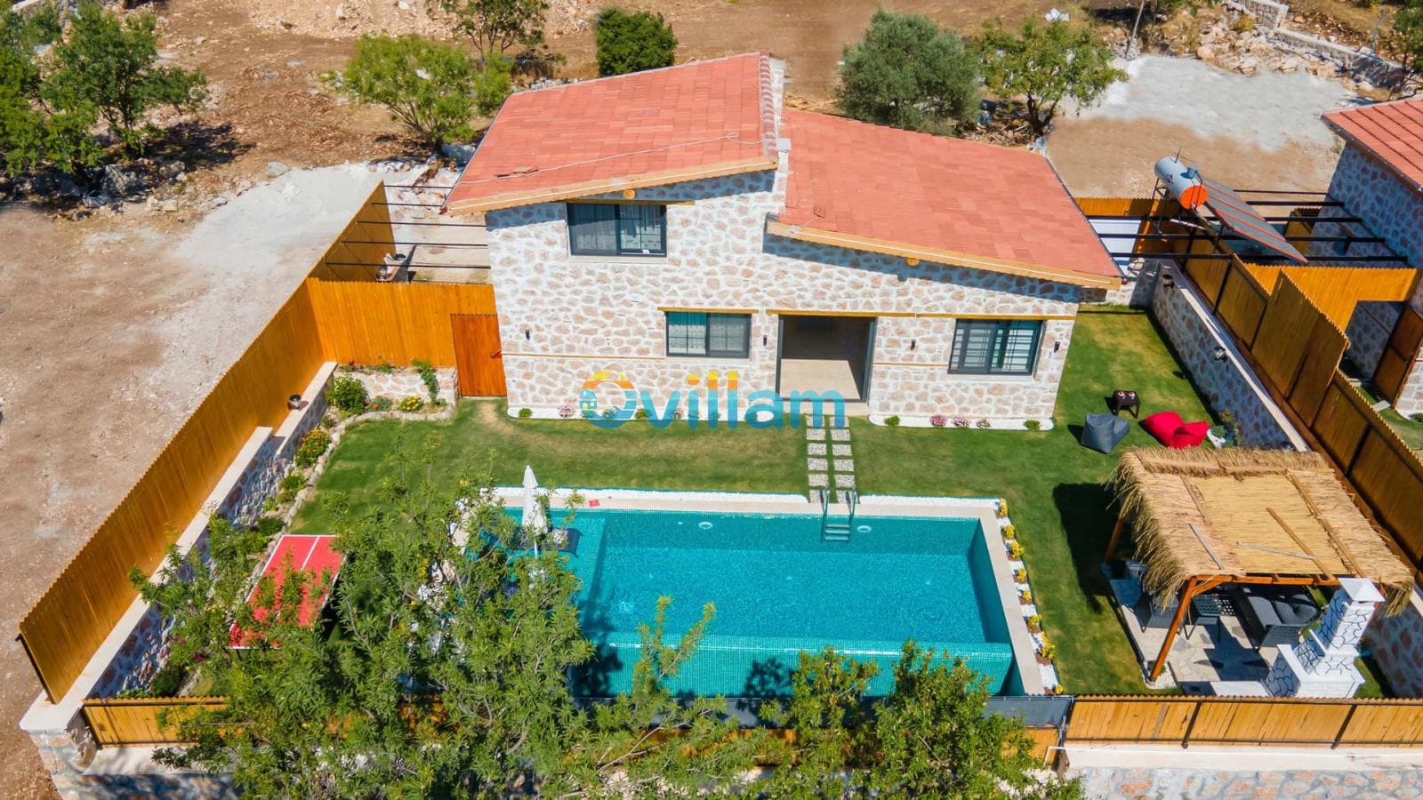Kuş bakışı görünümde taş villa, bahçesi, havuzu ve çardak alanı.