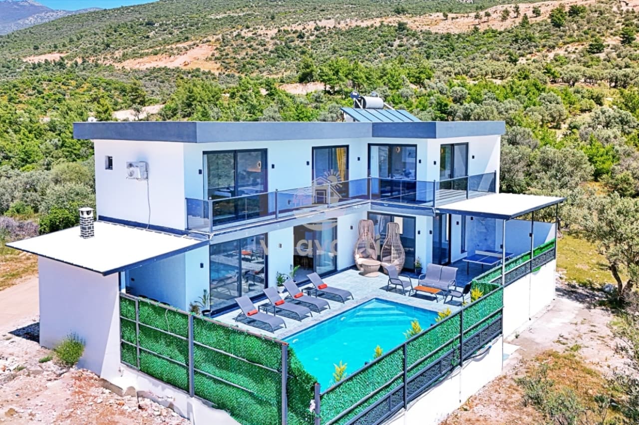 Doğa içinde, özel havuzlu ve şezlonglu iki katlı modern villa dış cephesi.