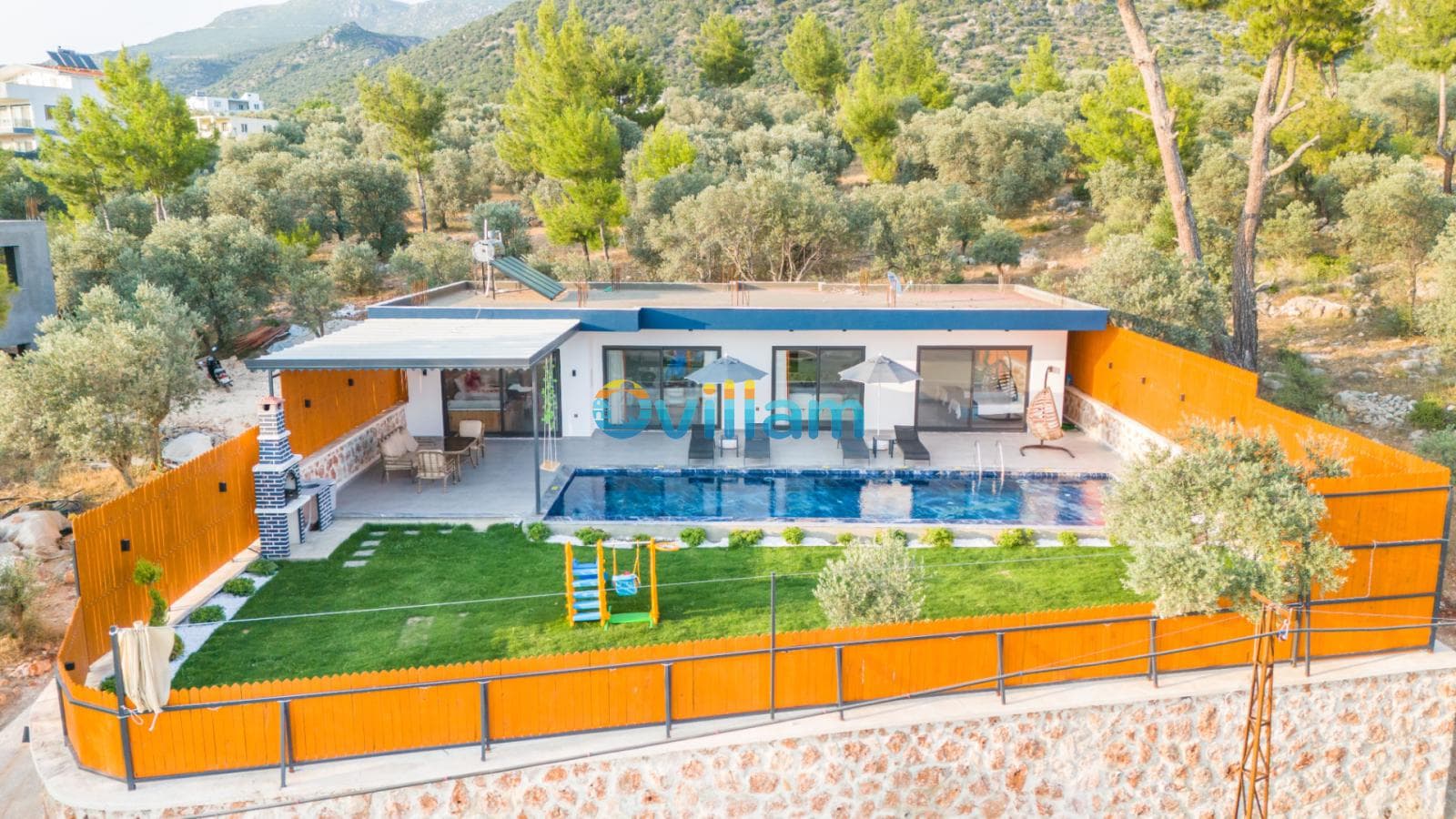 Yeşil ağaçlarla çevrili, havuzlu, bahçesinde çocuk oyun parkı bulunan tek katlı villa.