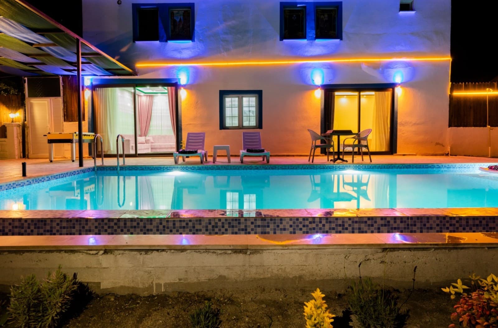 Gece aydınlatmalı havuz ve arka planda villanın ışıklı dış cephesi.