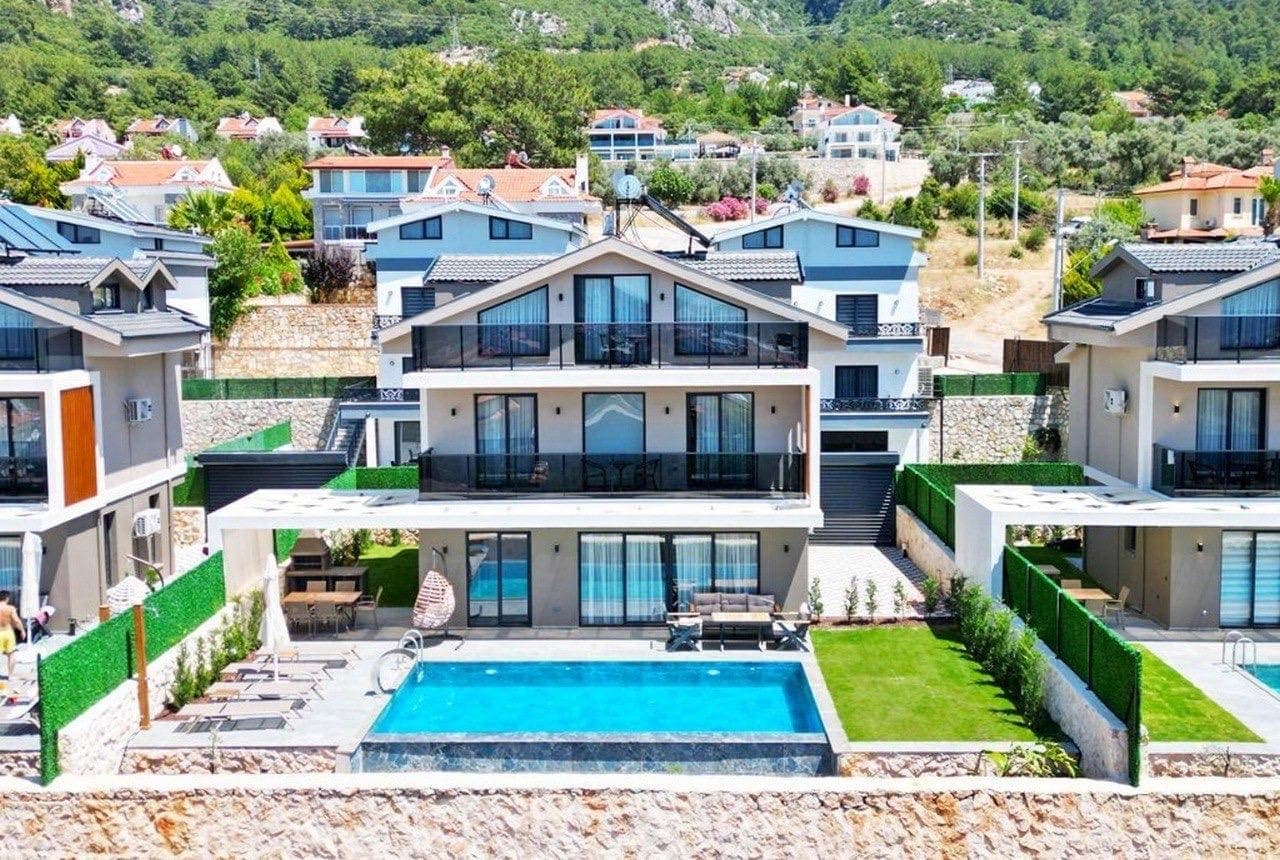 Özel havuzlu, teraslı ve çim bahçeli çok katlı villanın genel dış görünümü.