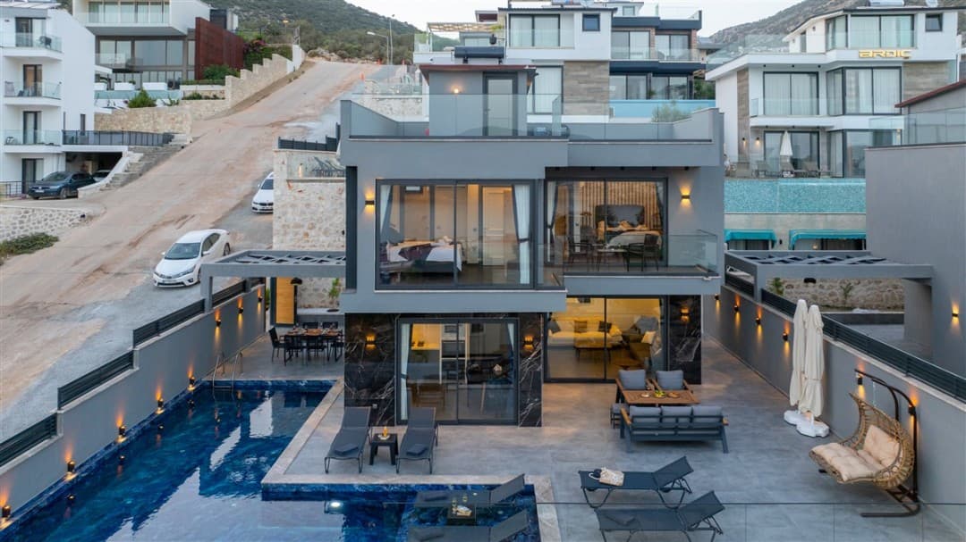 Özel havuzlu, geniş teraslı, modern mimariye sahip gri dış cepheli iki katlı villa.