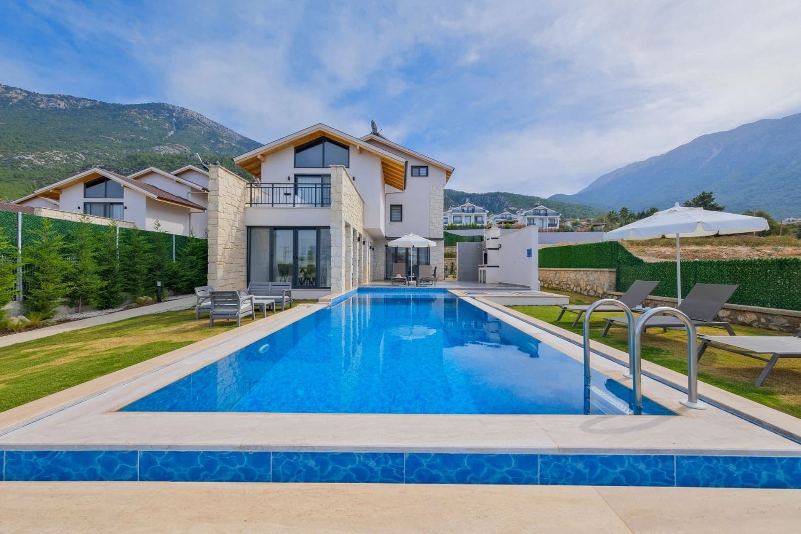 Dağ manzaralı, bahçeli ve özel yüzme havuzlu modern villa dış cephesi.