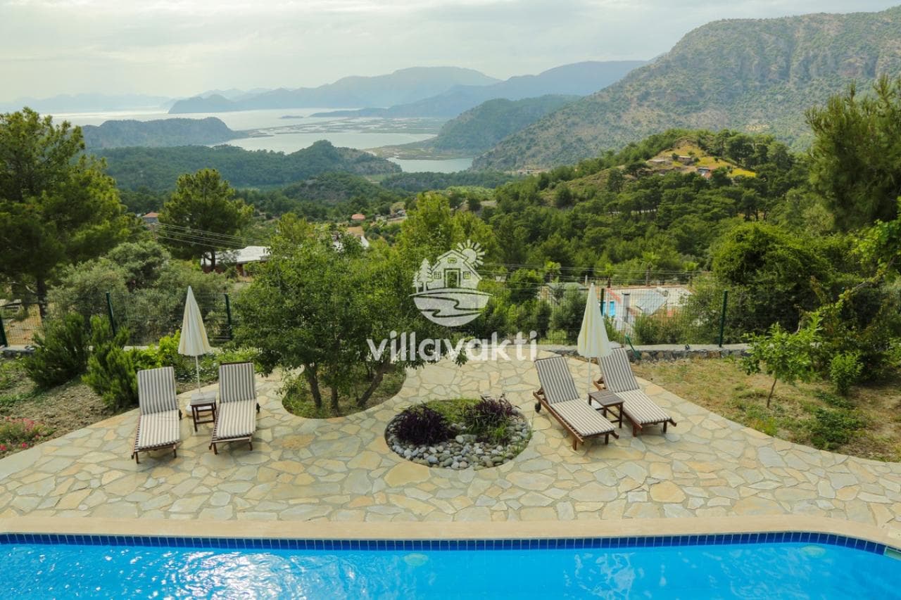 Doğa ve deniz manzaralı terasta şezlonglar, şemsiyeler ve ön planda havuz kenarı.