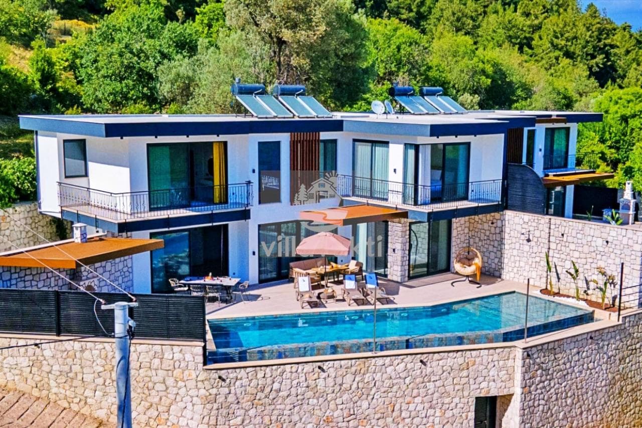 Taş duvarlı bahçesi, özel havuzu, şezlongları ve yemek masası olan iki katlı villa dış cephesi.