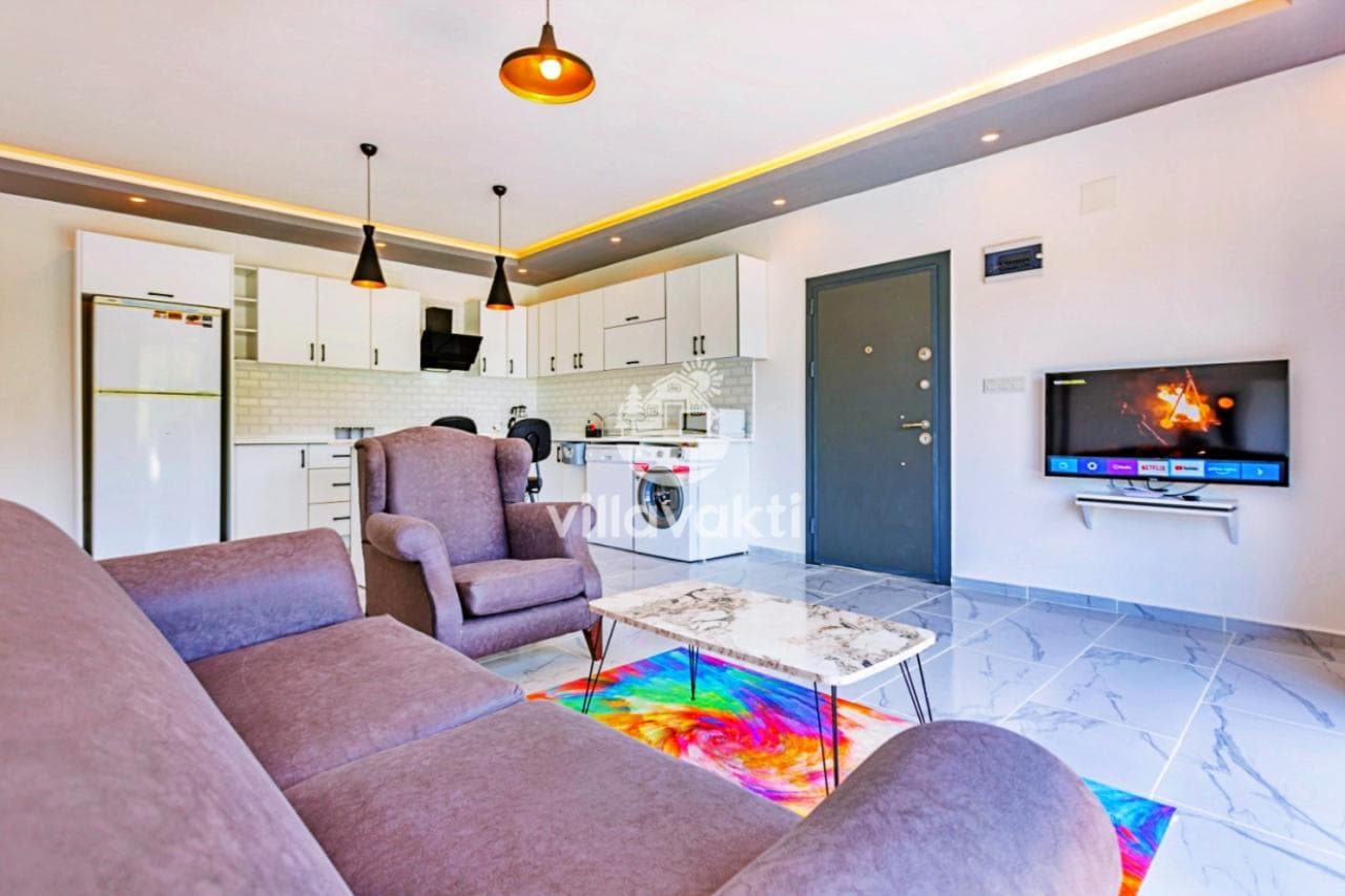 Koltuk takımı, TV ve arkada açık mutfağın yer aldığı oturma alanı.