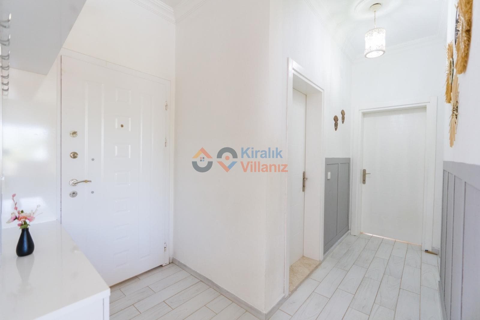 Beyaz kapılı, açık renk zeminli ve sade dekorasyonlu villa giriş holü.