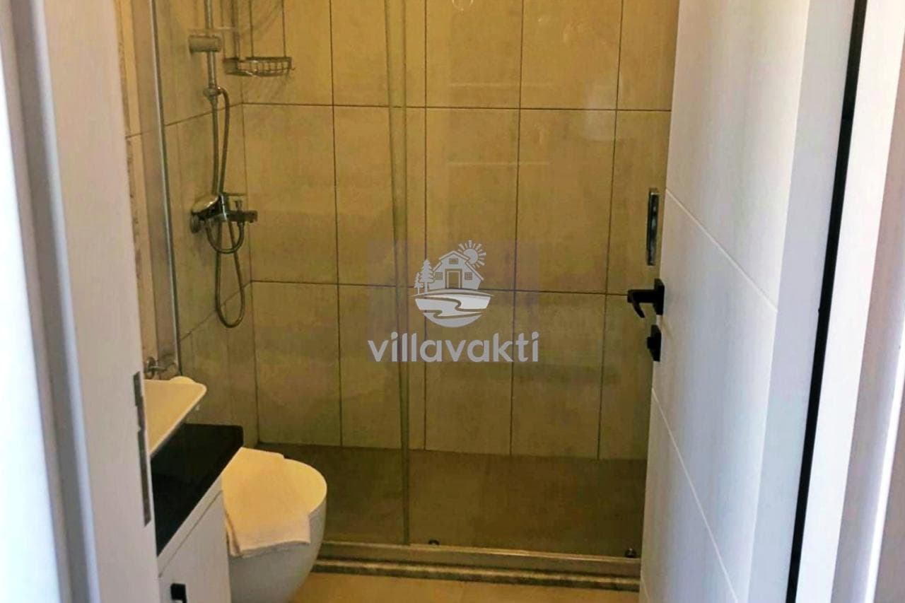 Cam duşakabin, klozet ve lavabonun yer aldığı fayans kaplı banyo.
