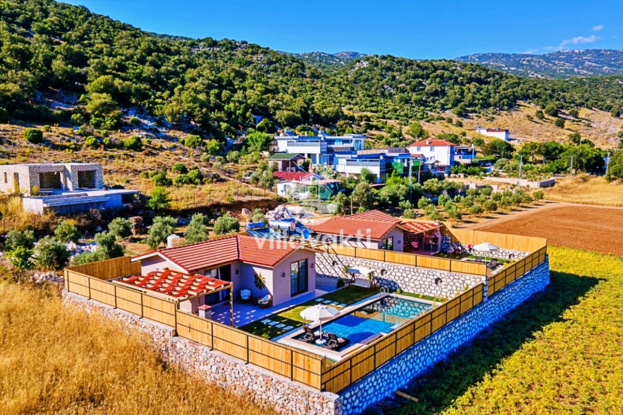 Kırsal alanda, etrafı taş duvarla çevrili, havuzlu tek katlı villa.