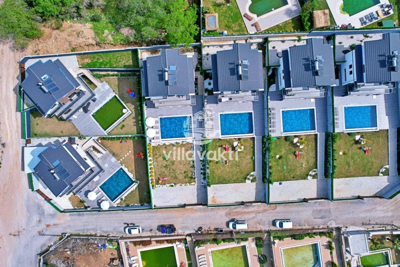 Kuş bakışı görünümde yan yana dizilmiş, özel havuzlu ve bahçeli villalar.