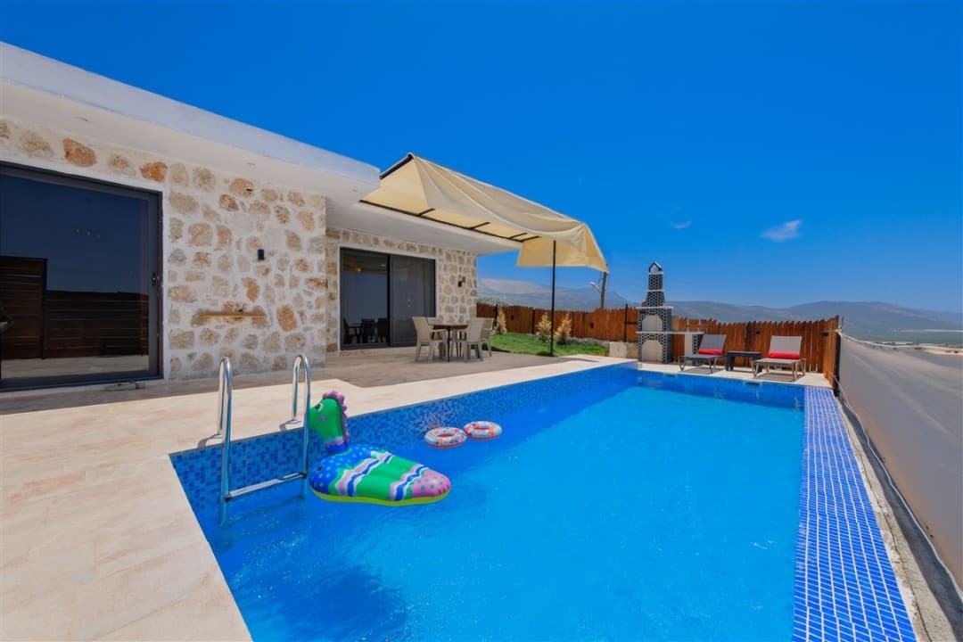 Havuzunda şişme deniz yatağı olan taş cepheli villa.