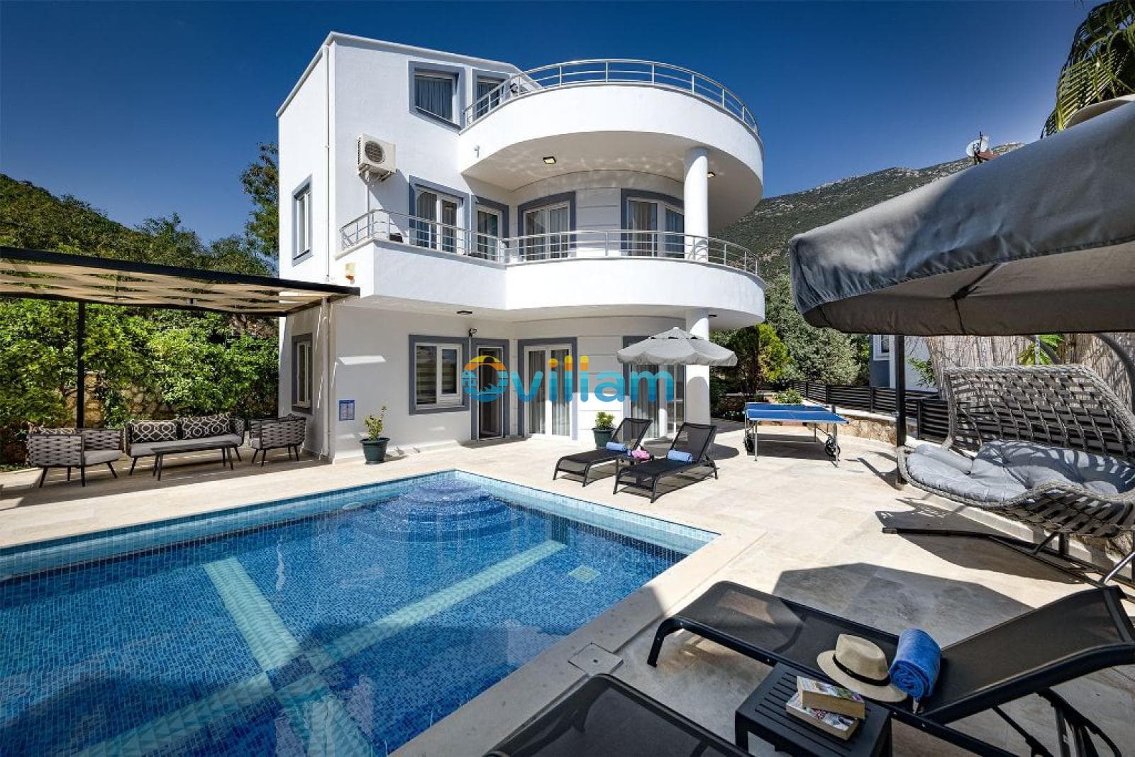 Özel yüzme havuzlu, şezlonglu ve geniş balkonlu iki katlı modern beyaz villa.