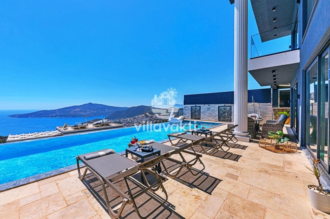 Deniz manzaralı sonsuzluk havuzu kenarında şezlonglar ve modern villa terası.