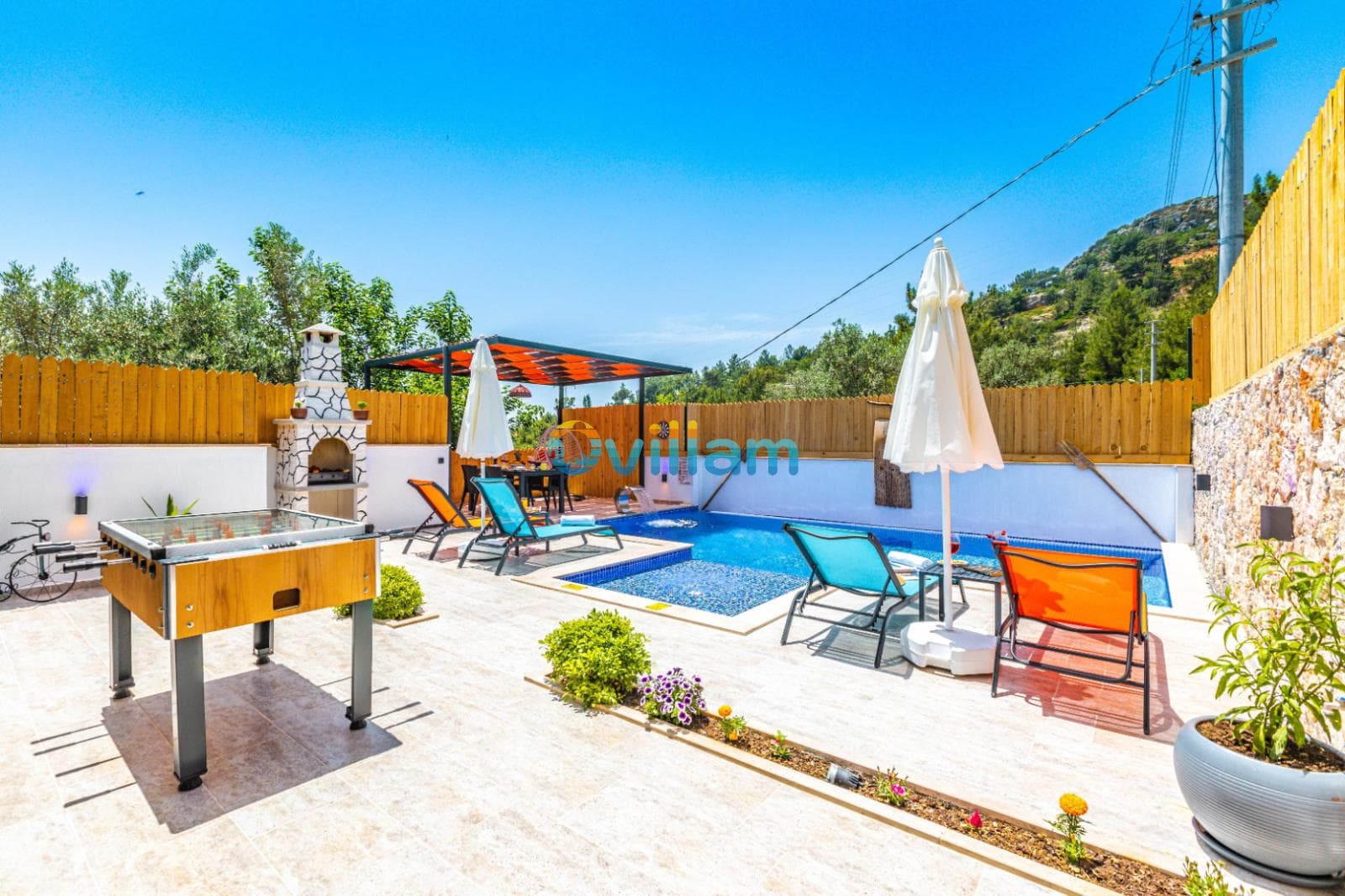 Havuz kenarında şezlonglar, masa tenisi, barbekü ve şemsiyeler bulunan güneşli bir teras.