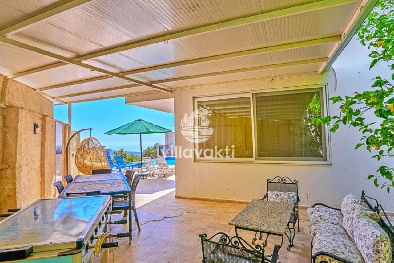 Veranda altında yemek masası, oturma grubu ve masa tenisi bulunan gölgelikli alan.