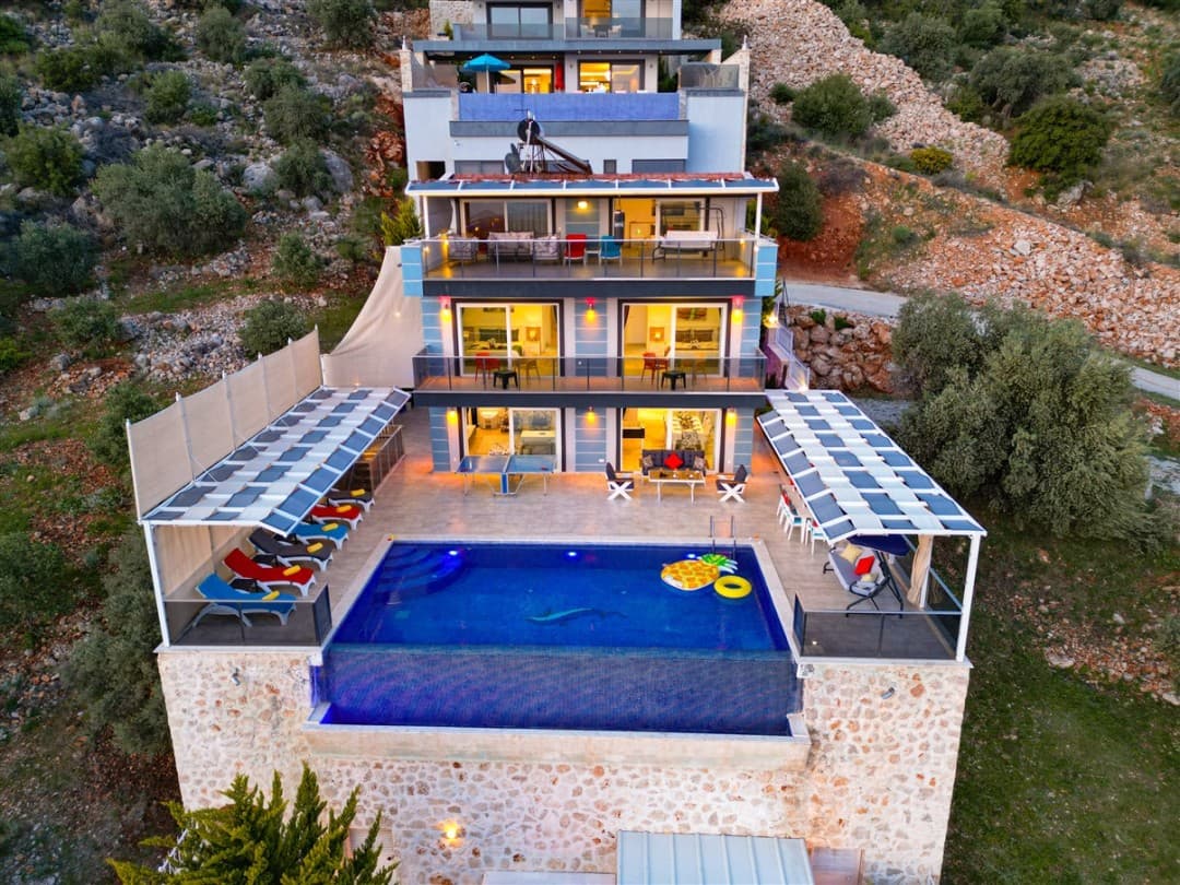 Yamaçta kurulu, sonsuzluk havuzlu, balkonlu ve güneşlenme teraslı çok katlı villa.