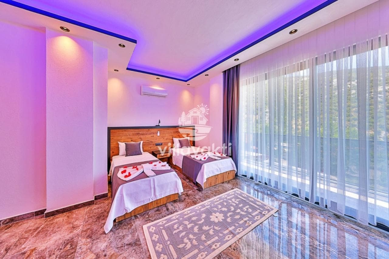 Mor led aydınlatmalı, iki tek kişilik yataklı, desenli halı bulunan modern yatak odası.