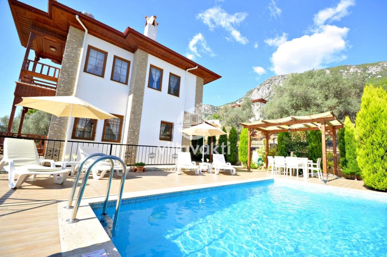 Ahşap detaylı iki katlı villa ve önündeki açık havuz.