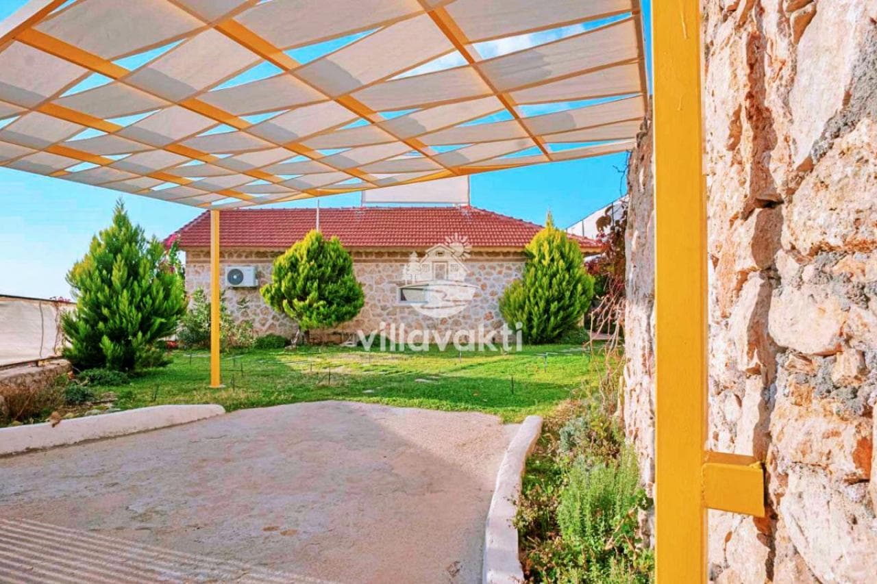 Bahçede çim alan, ağaçlar ve tavanı kaplı yürüyüş yolu.