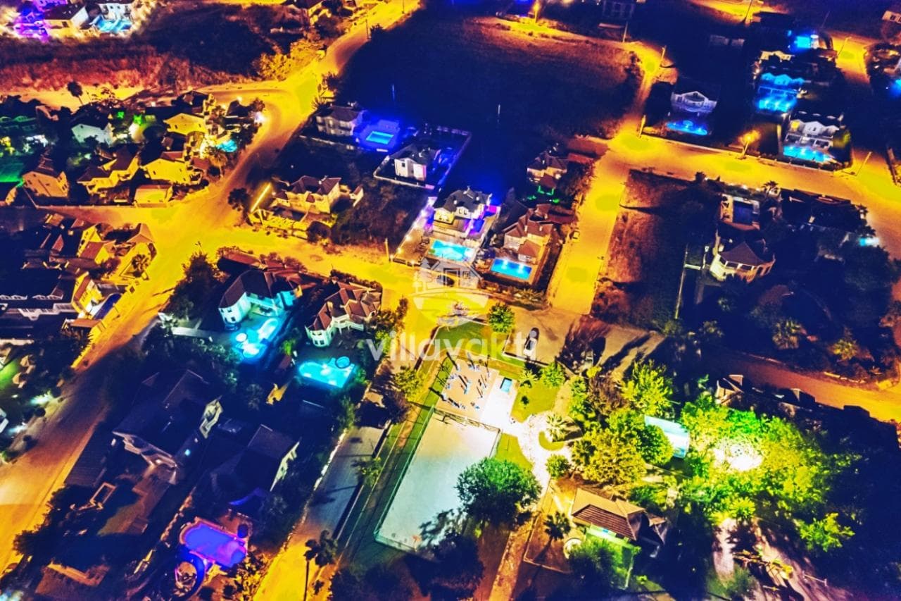 Gece vakti havuzlu villaların havadan aydınlatmalı görünümü.
